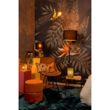 Stolička – v priestore s tropickou tapetou – stojí oproti stolíku s lampou. Na stene visí ďalšia lampa v tvare opice.