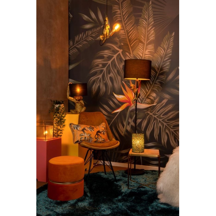 Stolička – v priestore s tropickou tapetou – stojí oproti stolíku s lampou. Na stene visí ďalšia lampa v tvare opice.