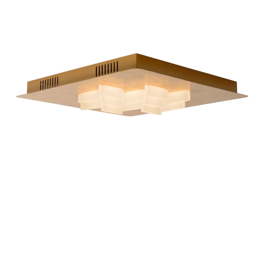 Stropné svietidlo svieti. Štvorcové zlaté telo svietidla obsahuje niekoľko mliečne bielych, kockovitých svetelných prvkov. Svietidlo je umiestnené na bielom pozadí.