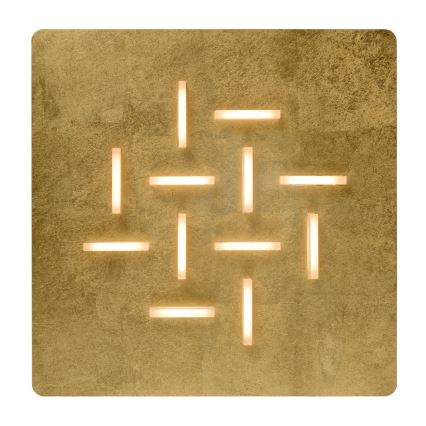 Zlatá štvorcová nástenná lampa svieti. Svetlo vychádza z úzkych, obdĺžnikových otvorov usporiadaných v pravidelnom geometrickom vzore. Pozadie je zlatožltej farby s textúrovaným povrchom.