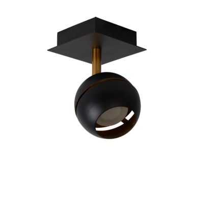 Svietidlo svieti. Čierna guľová lampa na zlatej tyči je pripevnená k štvorcovej čiernej základni. Svetlo je zavesené na strope.