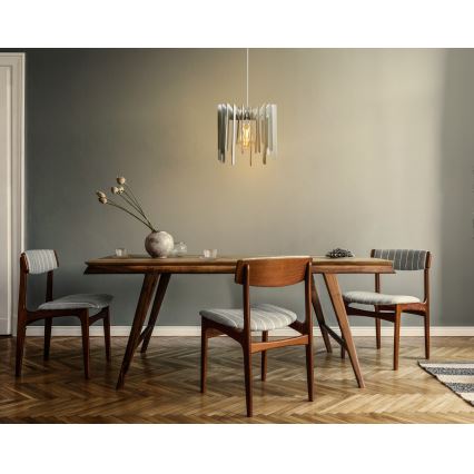 Svietidlo s drevenými lamelami visí nad jedálenským stolom. Štyri drevené stoličky s látkovým poťahom sú umiestnené okolo stola. Prostredie tvorí svetlá miestnosť s parketovou podlahou a zelenou stenou.