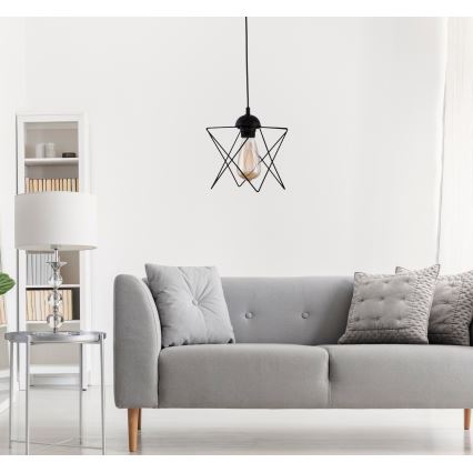 Závesné svietidlo s geometrickým tienidlom visí v obývacej izbe nad sivou pohovkou. Svietidlo obsahuje žiarovku s teplým svetlom. V miestnosti sa nachádza aj konferenčný stolík a knižnica.