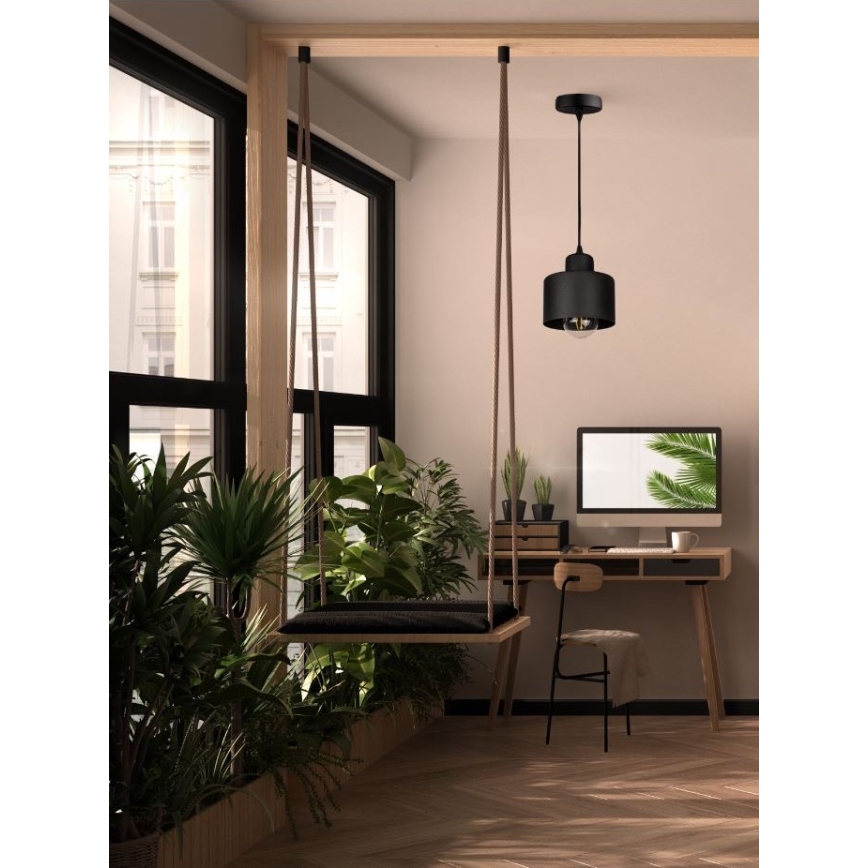 Závesná hojdacia sedačka visí v priestore s oknami a zeleňou. Nad pracovnou plochou s počítačom visí čierna závesná lampa.