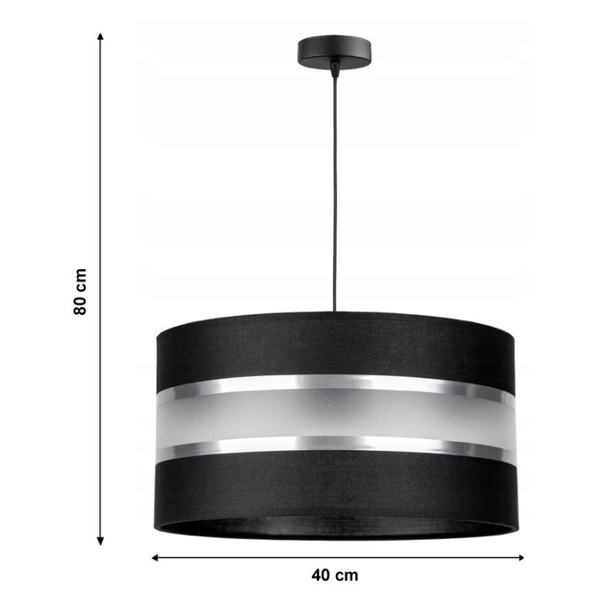 Závesné svietidlo visí zo stropu. Má valcovitý tienidlo z čiernej látky s dvoma striebornými pásikmi a priesvitným materiálom. Rozmery: priemer 40 cm, výška 80 cm.