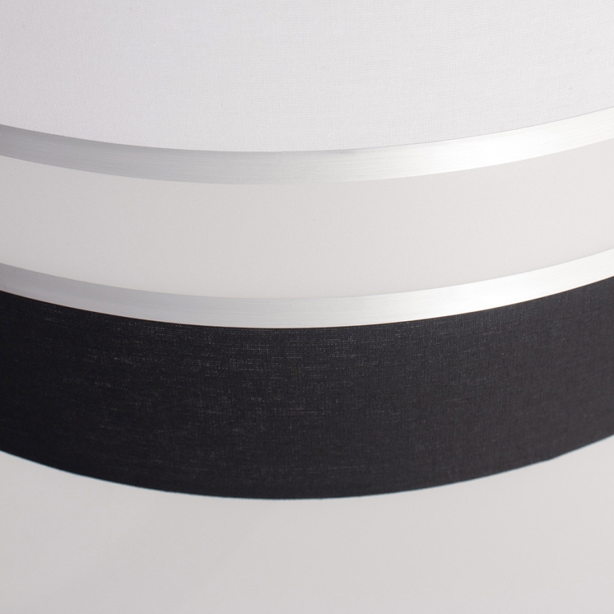 Dvojvrstvový tienidlo svietidla, zložené z bieleho a čierneho textilného materiálu, je oddelené úzkym strieborným pásom. Biely vrchný diel je hladký, spodný čierny je textúrovaný.