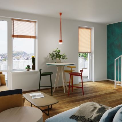 Jedálenský stôl so štyrmi stoličkami stojí v svetlej izbe s drevenou podlahou. Nad stolom visí stropné svietidlo. Okná sú vybavené žalúziami.