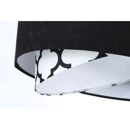 Dvojvrstvový tienidlo svietidla visí. Vrchná časť je z čiernej látky, spodná je biela s čiernym geometrickým vzorom. Tienidlo je osvetľovací prvok.