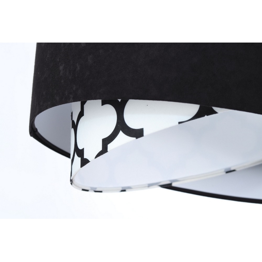 Dvojvrstvový tienidlo svietidla visí. Vrchná časť je z čiernej látky, spodná je biela s čiernym geometrickým vzorom. Tienidlo je osvetľovací prvok.