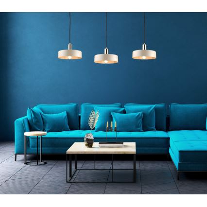 Tri kruhové závesné lampy s béžovými tienidlami a kovovými detailmi visia nad tmavomodrou rohovou sedačkou. Pred sedačkou sa nachádza nízky obdĺžnikový konferenčný stolík. Pozadie tvorí tmavomodrá stena.