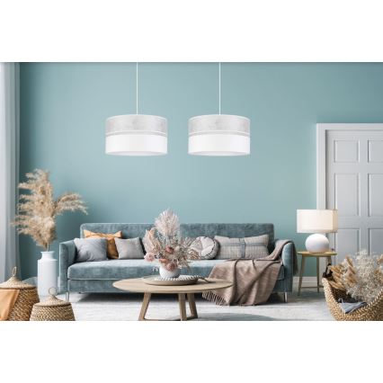 Dve závesné lampy visia nad sedačkou v obývacej izbe. Lampa má valcovitý tienidlo s dvoma farebnými časťami: svetlosivou a bielou. Izba je zariadená moderným nábytkom a dekoráciami.