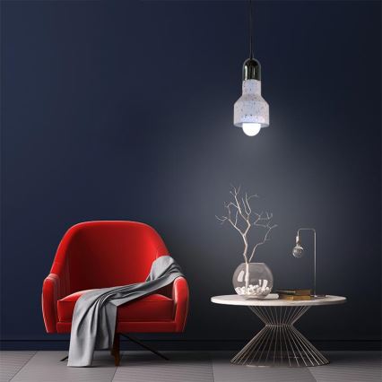 Červené kreslo stojí v miestnosti s tmavomodrými stenami. Nad ním visí biela bodkovaná lampa. Na nízkom kovovom stolíku je váza so suchou vetvičkou a kniha.