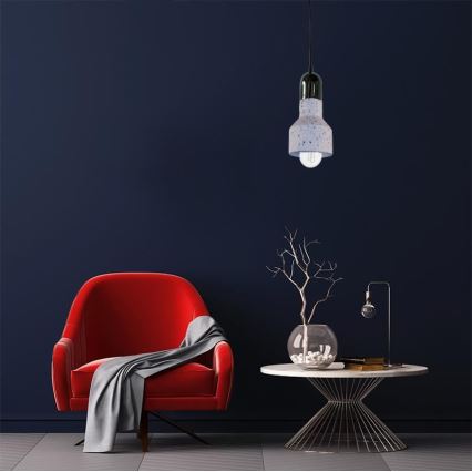 Svietidlo visí z tmavomodrej steny. Je to betónová lampa s bielymi škvrnami, s viditeľnou žiarovkou. Nachádza sa v miestnosti s červeným kreslom a konferenčným stolíkom.