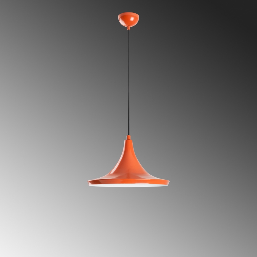 Oranžová závesná lampa visí zo stropu. Jej tienidlo má tvar obráteného zvona. Pozadie je svetlosivé, prechádza do tmavšej sivej.