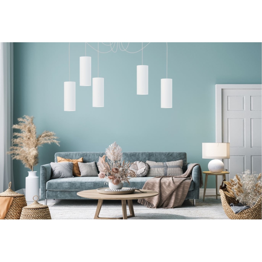 Päť valcovitých závesných lámp visí v obývacej izbe. Lampa je biela, svetlo svieti smerom dole. Izba obsahuje pohovku, konferenčný stolík a podlahovú lampu.