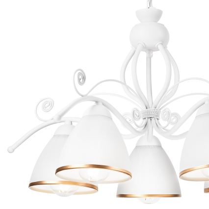 Biela závesná lampa s piatimi tienidlami visí z stropu. Tienidlá majú zlatý okraj. Konštrukcia lampy je ozdobná, s krivkami a ornamentami.