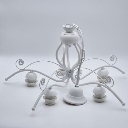 Biela kovová luster s piatimi ramenami visí. Rameno sú ozdobené ornamentami. Luster je umiestnený na bielom pozadí.