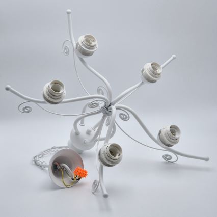 Biela kovová lusterová zostava leží rozložená na bielom povrchu. Päť vývodov na žiarovky je pripojených k rozvetvenému rámu. Súčasťou je aj stropný držiak s viditeľnou kabelážou a svorkovnicou.