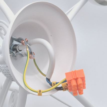 Biela svietidlová objímka s pripojenými vodičmi. Elektrické káble sú zapojené do oranžovej svorkovnice. Na vodičoch sú viditeľné označenia: „N“, „L“ a „T“.
