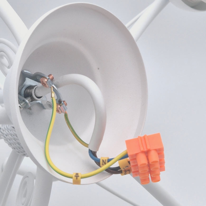 Biela svietidlová objímka s pripojenými vodičmi. Elektrické káble sú zapojené do oranžovej svorkovnice. Na vodičoch sú viditeľné označenia: „N“, „L“ a „T“.