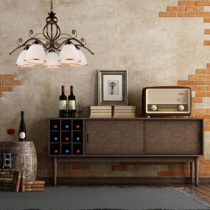 Krídlový luster s piatimi tienidlami visí nad drevenou skrinkou s vinotékou. Na skrinke stojí staré rádio a knihy. Stena je z tehál a omietky.