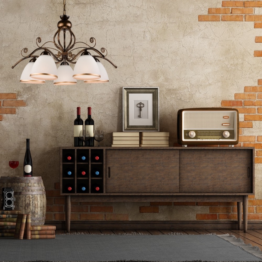 Krídlový luster s piatimi tienidlami visí nad drevenou skrinkou s vinotékou. Na skrinke stojí staré rádio a knihy. Stena je z tehál a omietky.