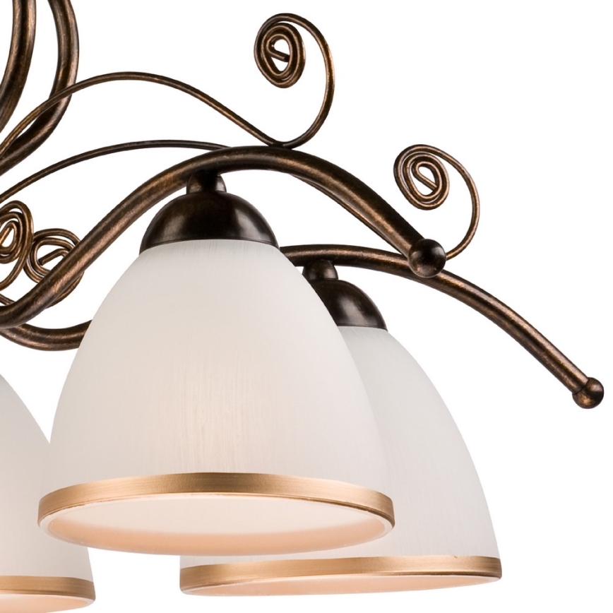 Viacramenné bronzové svietidlo s ozdobnými závitmi drží niekoľko mliečnobielych tienidiel s pozláteným okrajom. Tienidlá sú z matného skla. Svietidlo je zavesené.