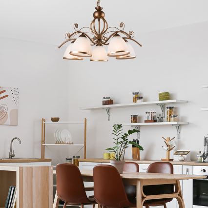 Lustro s viacerými tienidlami visí v miestnosti. Hnedé kožené kreslo stojí na tmavej podlahe pred stenou.