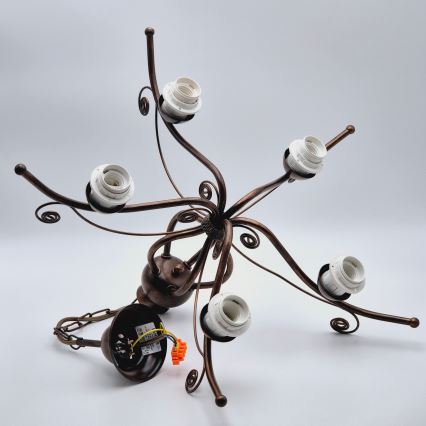 Kovová lampa s krivkami a ozdobami nesie tri mliečne tienidlá s pozláteným lemom. Tienidlá sú kužeľovitého tvaru. Lampa je umiestnená na bielom pozadí.