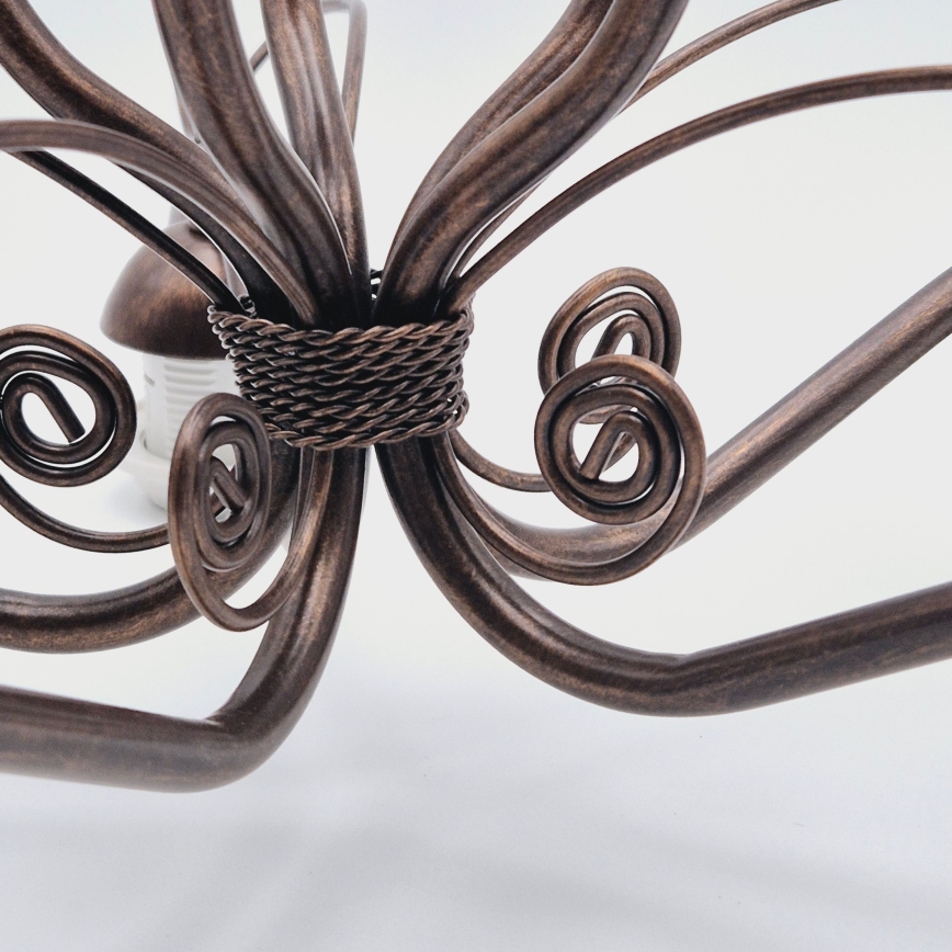 Medený stropný kryt s mierne nerovným povrchom je pripevnený k kovovej tyči. Kryt je zvrchu otvorený a má tvar zvona.