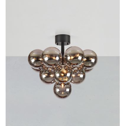 Stropná lampa s čiernym držiakom osvetľuje priestor pomocou zoskupenia niekoľkých tmavosivých sklenených gúľ. Gule sú rôznej veľkosti a niektoré obsahujú žiarovky.