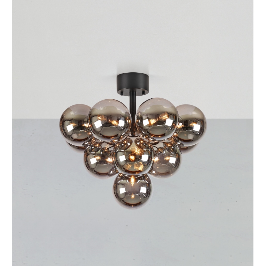 Stropná lampa s čiernym držiakom osvetľuje priestor pomocou zoskupenia niekoľkých tmavosivých sklenených gúľ. Gule sú rôznej veľkosti a niektoré obsahujú žiarovky.