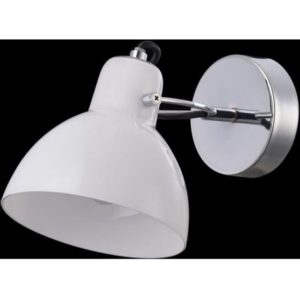 Biela nástenná lampa s kovovou konštrukciou a tienidlom osvetľuje priestor. Lampa je pripevnená k stene pomocou kovového držiaku.