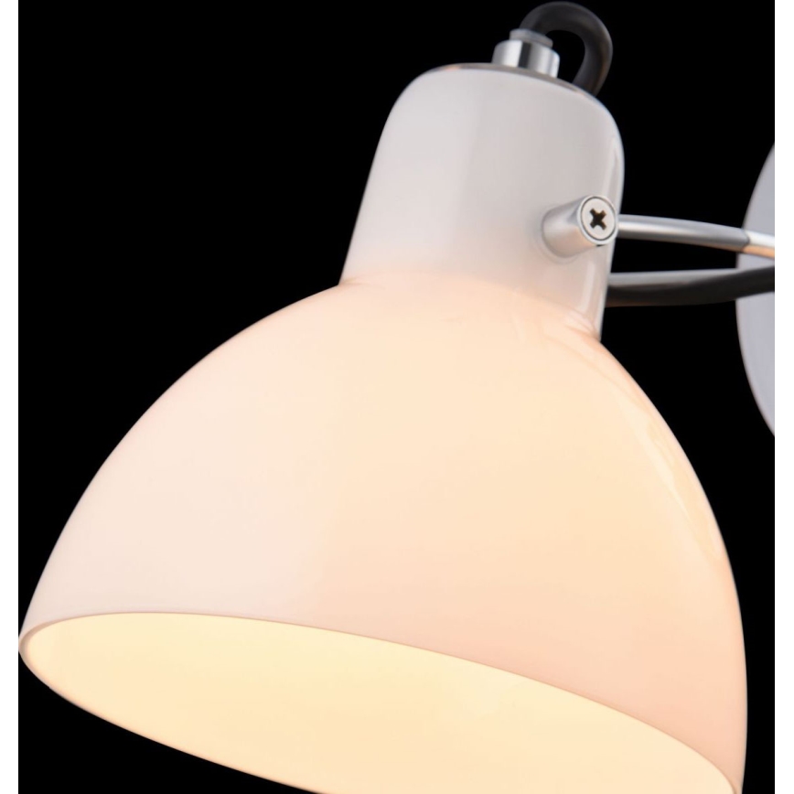 Biela stolová lampa s polguľovitým tienidlom svieti. Je pripevnená k kovovému ramenu. Tmavé pozadie.