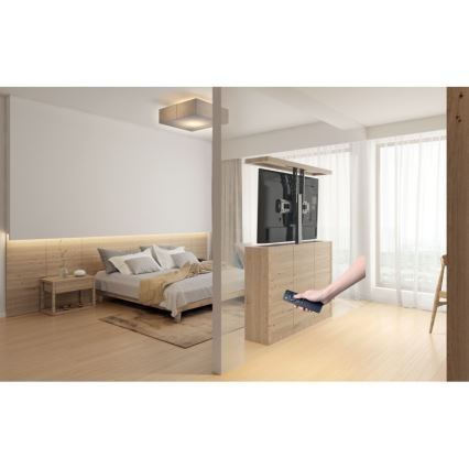 Televízor sa zdvíha z nábytku pomocou diaľkového ovládača v spálni s posteľou a drevenou podlahou.