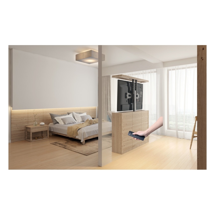 Televízor sa zdvíha z nábytku pomocou diaľkového ovládača v spálni s posteľou a drevenou podlahou.