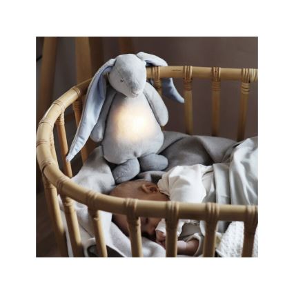 Plyšový zajačik s mäkkým svetlom je umiestnený v bambusovej kolíske pri spiacom dojčaťu. Zajačik svieti jemným svetlom.