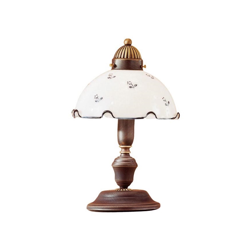 Stolová lampa s bielym tienidlom zdobeným drobnými kvietkami svieti. Tienidlo je zvlnené na okraji a má hnedý drevený podstavec. Lampa je umiestnená na bielom pozadí.