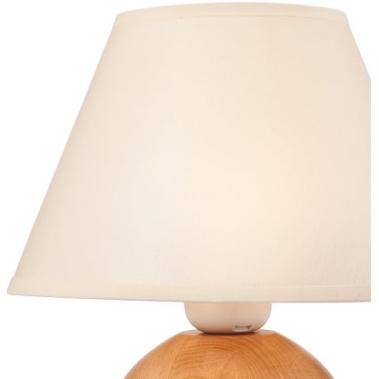 Stolová lampa s krémovým tienidlom je umiestnená na drevenom podstavci. Tienidlo je kužeľovité a prilieha na guľovitý drevený základ.