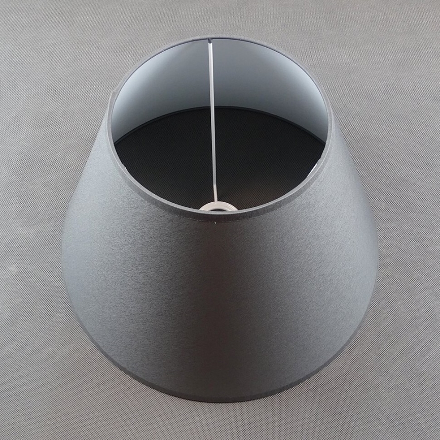 Tmavosivý kužeľovitý tienidlo s vnútornou svetlou časťou je položené na sivom podklade. Tienidlo je z látky, vidieť tenký priehľadný kábel.