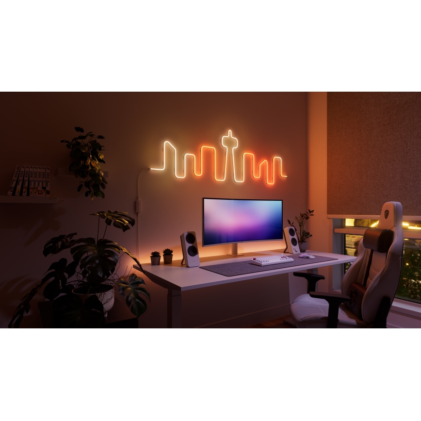 Neonové svetlo vo forme mestskej panorámy svieti na stene pracovne. Pracovný stôl obsahuje počítač, klávesnicu, reproduktory a herovskú stoličku. Okolitým prvkom sú izbové rastliny.