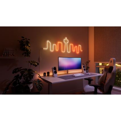 Neonové svetlo vo forme mestskej panorámy svieti na stene pracovne. Pracovný stôl obsahuje počítač, klávesnicu, reproduktory a herovskú stoličku. Okolitým prvkom sú izbové rastliny.