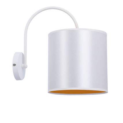 Nástená lampa s bielym tienidlom valcového tvaru a zlatým vnútorným okrajom je pripevnená na stene pomocou bielej kovovej konštrukcie. Lampa je otočená smerom nadol.