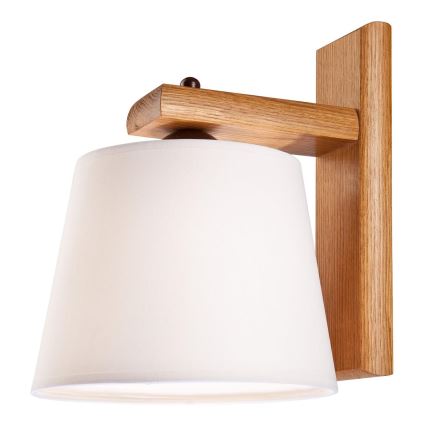Drevená nástenná lampa s bielym tienidlom je pripevnená na stene. Lampa je umiestnená v interiéri s výhľadom na okno s dreveným rámom a rastlinami na parapete.