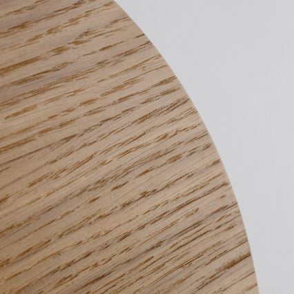 Drevený disk leží na svetlom pozadí. Jeho povrch vykazuje výraznú drevenú štruktúru s viditeľnými vláknami.