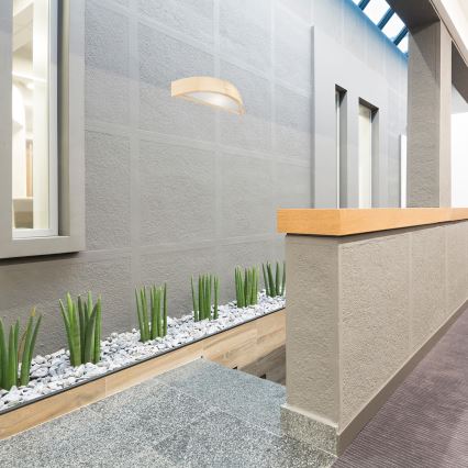 Drevený rám obklopuje svetelný zdroj. Rám je svetlohnedý, zakrivený a má viditeľnú štruktúru dreva. Svetelný zdroj je čiastočne viditeľný cez priesvitnú časť.