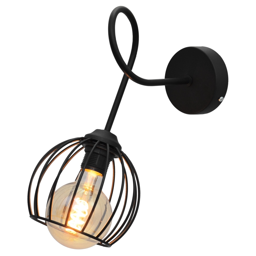 Čierna nástenná lampa s kovovou klietkou okolo žiarovky sa nachádza na stene. Lampa je pripevnená k stene pomocou kruhového držiaka. Svetlo je zapnuté.