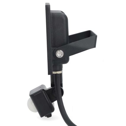 Čierne vonkajšie LED svetlo s pohybovým senzorom je pripojené k elektrickému káblu. Svetlo je namontované na nastaviteľnom držiaku. Je zobrazené na bielom pozadí.