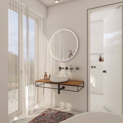 Kúpeľňová umývadlová zostava s okrúhlym zrkadlom s LED osvetlením je umiestnená na drevenom pulte s kovovou konštrukciou. Vedľa sa nachádza dvere do ďalšej časti kúpeľne. Za umývadlom je vidieť závesy a okno s výhľadom na terasu.