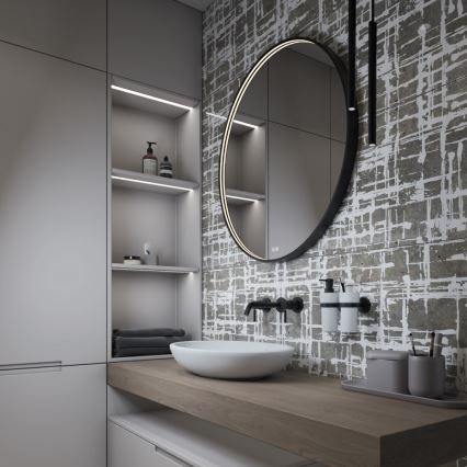 Kúpeľňová umývadlová misa s batériou je umiestnená na drevenom pulte pred veľkým okrúhlym zrkadlom so vstavaným podsvietením. Steny sú obložené dlaždicami s abstraktným vzorom. Na pulte sú aj doplnky, ako dávkovače mydla a stojan na zubné kefky.